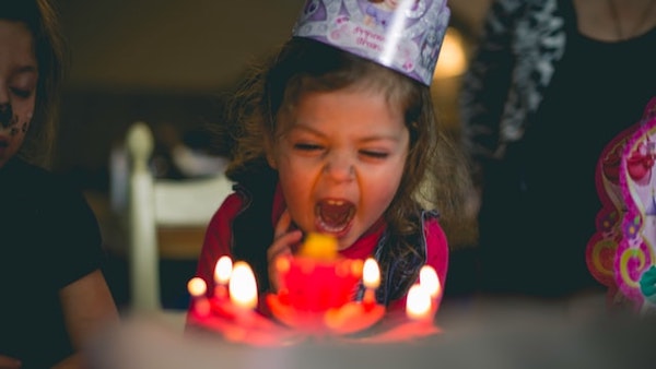 誕生日ケーキのろうそくを笑顔で吹き消す子供
